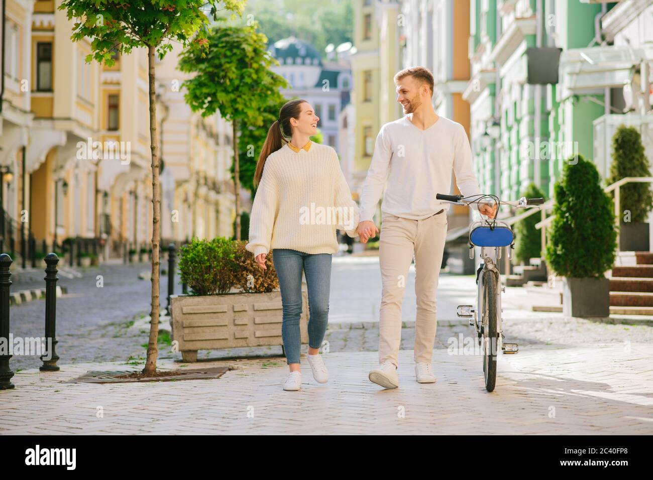 Mann mit Fahrrad und Frau halten Hand, die einander anschaut Stockfoto