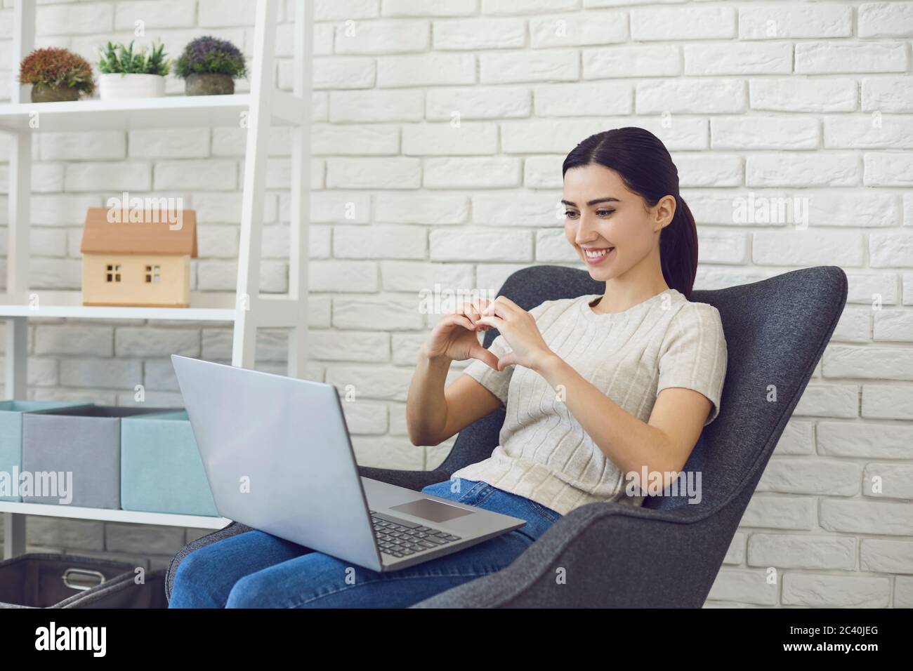 Junge Brünette chatten online, so dass Herd Zeichen. Seitenansicht der Videoanrufankommunikation. Stockfoto