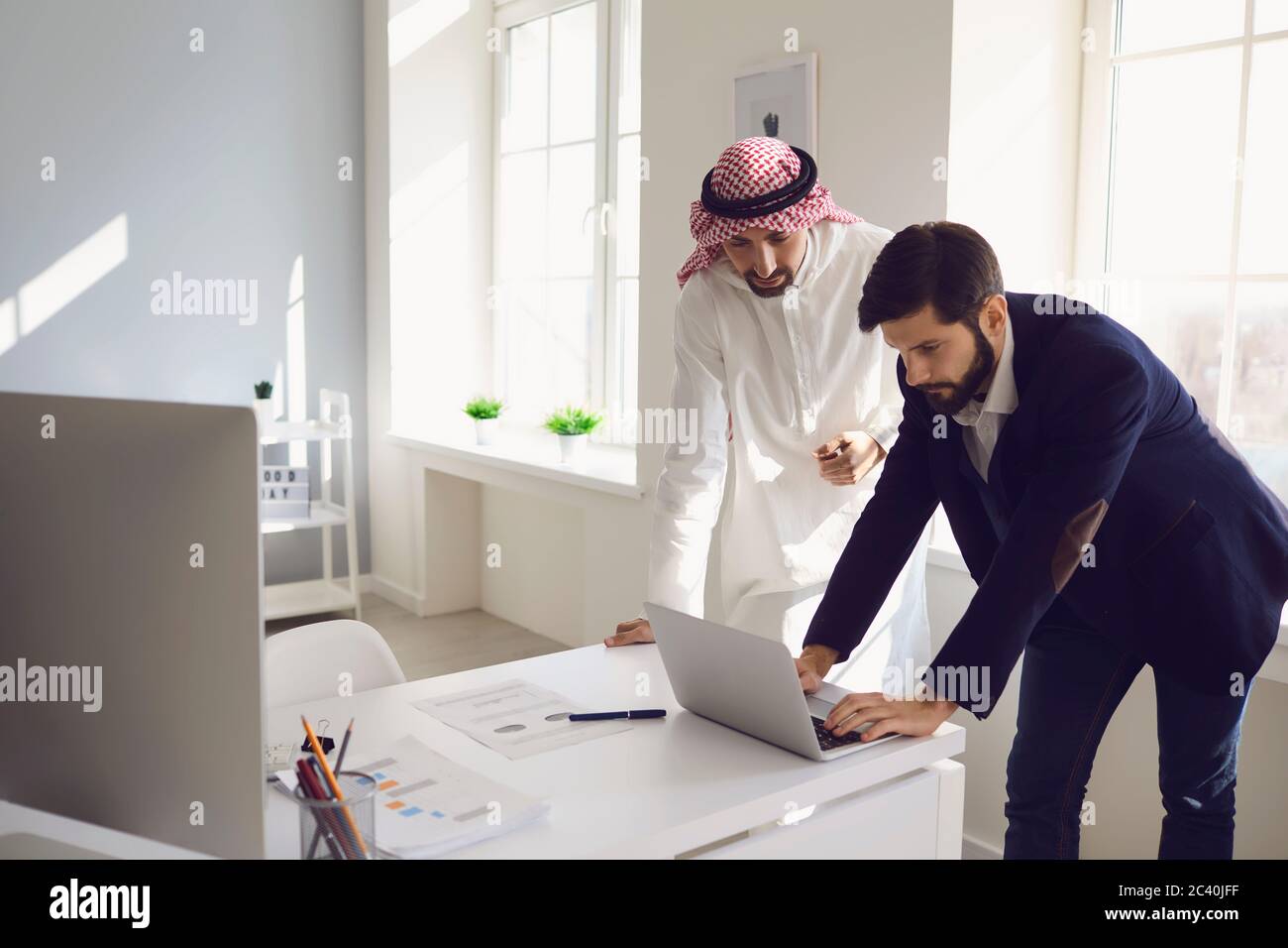 Arabische und europäische Unternehmer arbeiten zuversichtlich in einem weißen Büro. Stockfoto