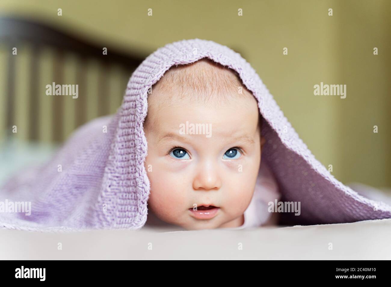 Ein schönes neugeborenes blauäugiges Mädchen liegt auf ihrem Bauch Und schaut nach oben Stockfoto