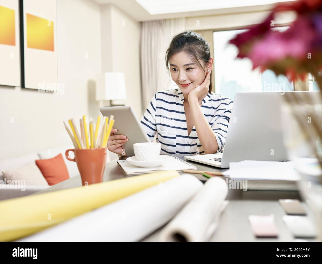 Junge asiatische Geschäftsfrau arbeitet zu Hause mit Laptop-Computer und digitalen Tablet (Kunstwerk im Hintergrund digital verändert) Stockfoto