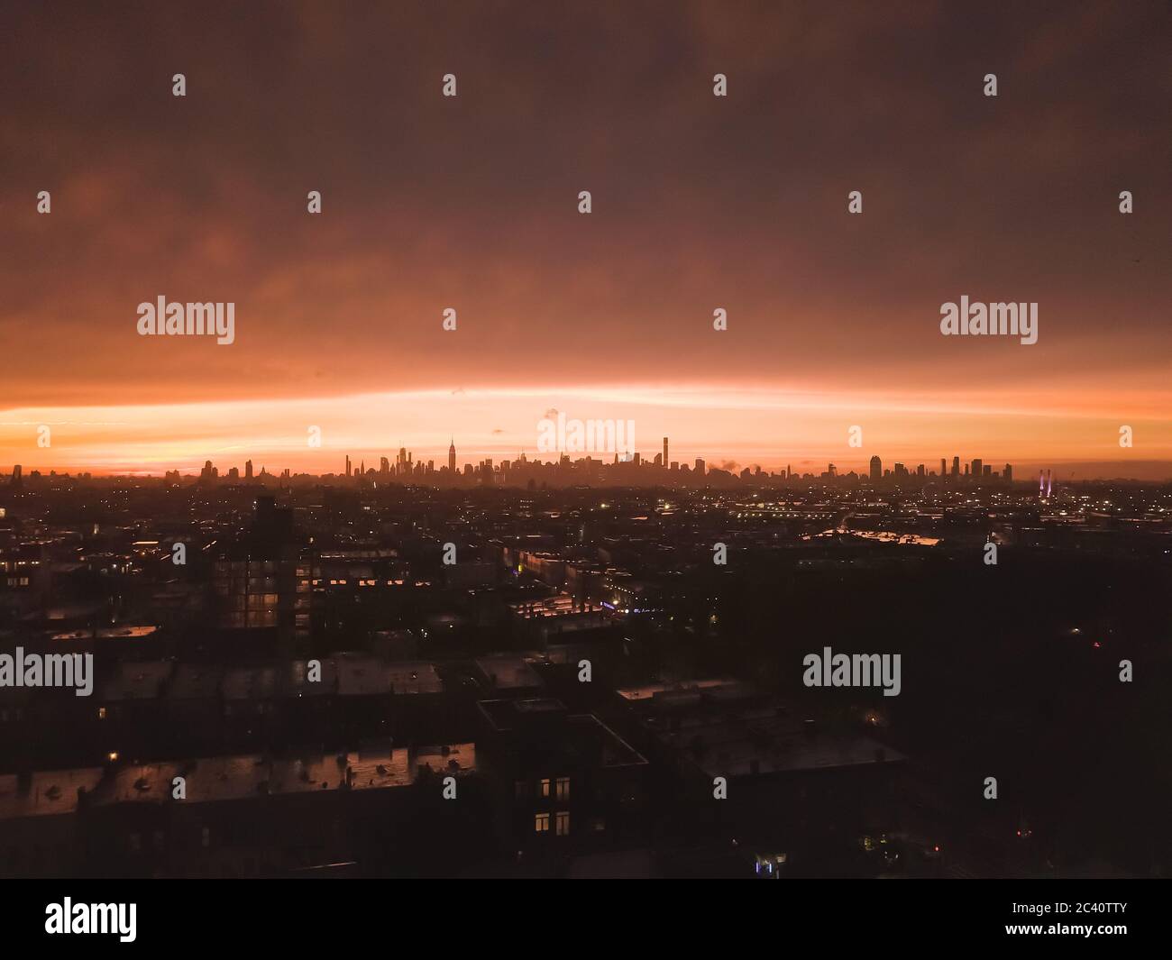 Luftaufnahme von Brooklyn über die weit entfernte Skyline von Manhattan in der Ferne nach Sonnenuntergang mit Feuerrotes Licht und Skyscraper Silhouette Stockfoto