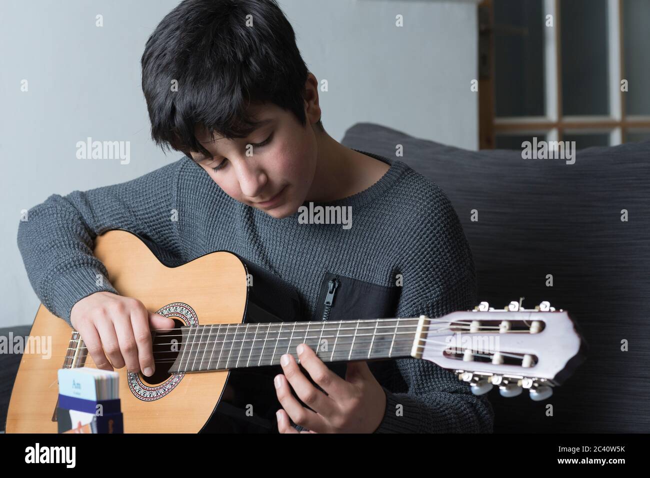 Teenager Junge, Alter 12-13 spielt akustische Gitarre Stockfoto