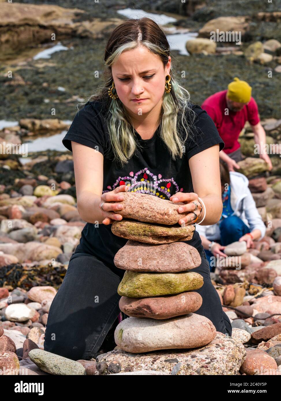 Frau balanciert Steine, European Stone Stacking Championship, Eye Cave Beach, Dunbar, East Lothian, Schottland, Großbritannien Stockfoto