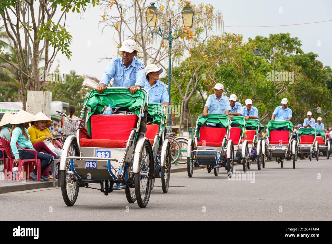 Männer, die ihr Pedal fuhren, fuhren tagsüber leere Taxis durch die Straßen von hoi an Stockfoto