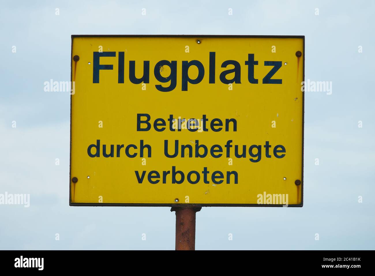 Gelbes Schild mit der Aufschrift: Flugplatz, Einflugverbot durch Unbefugte, in deutscher Sprache Stockfoto