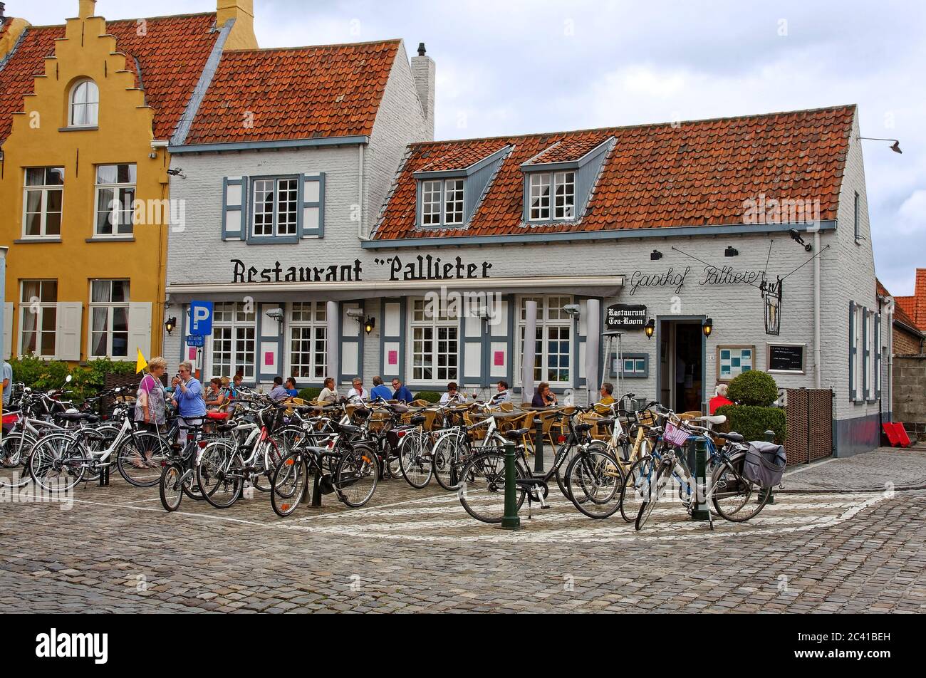 Restaurant Teestube, altes Gebäude, viele Fahrräder draußen, Kopfsteinpflaster, Menschen essen im Freien, am frühen Morgen, Europa, Damme, Belgien Stockfoto