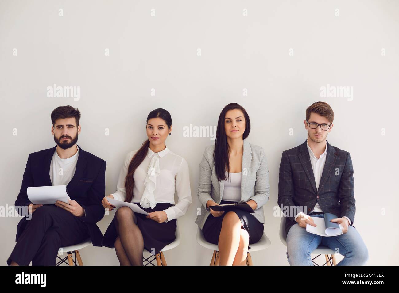 Geschäftsleute, die auf die Einstellung von Bewerbungsgesprächen warten, sitzen auf einem Stuhl im Büro. Stockfoto