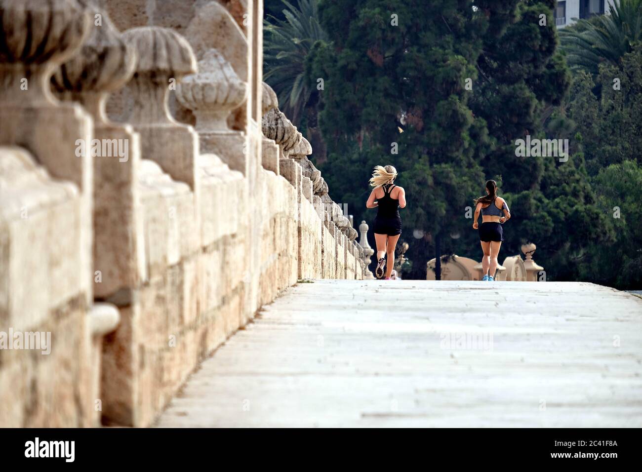 Mädchen beim Joggen auf einer Brücke über die Gärten von Turia in Valencia, Spanien Stockfoto