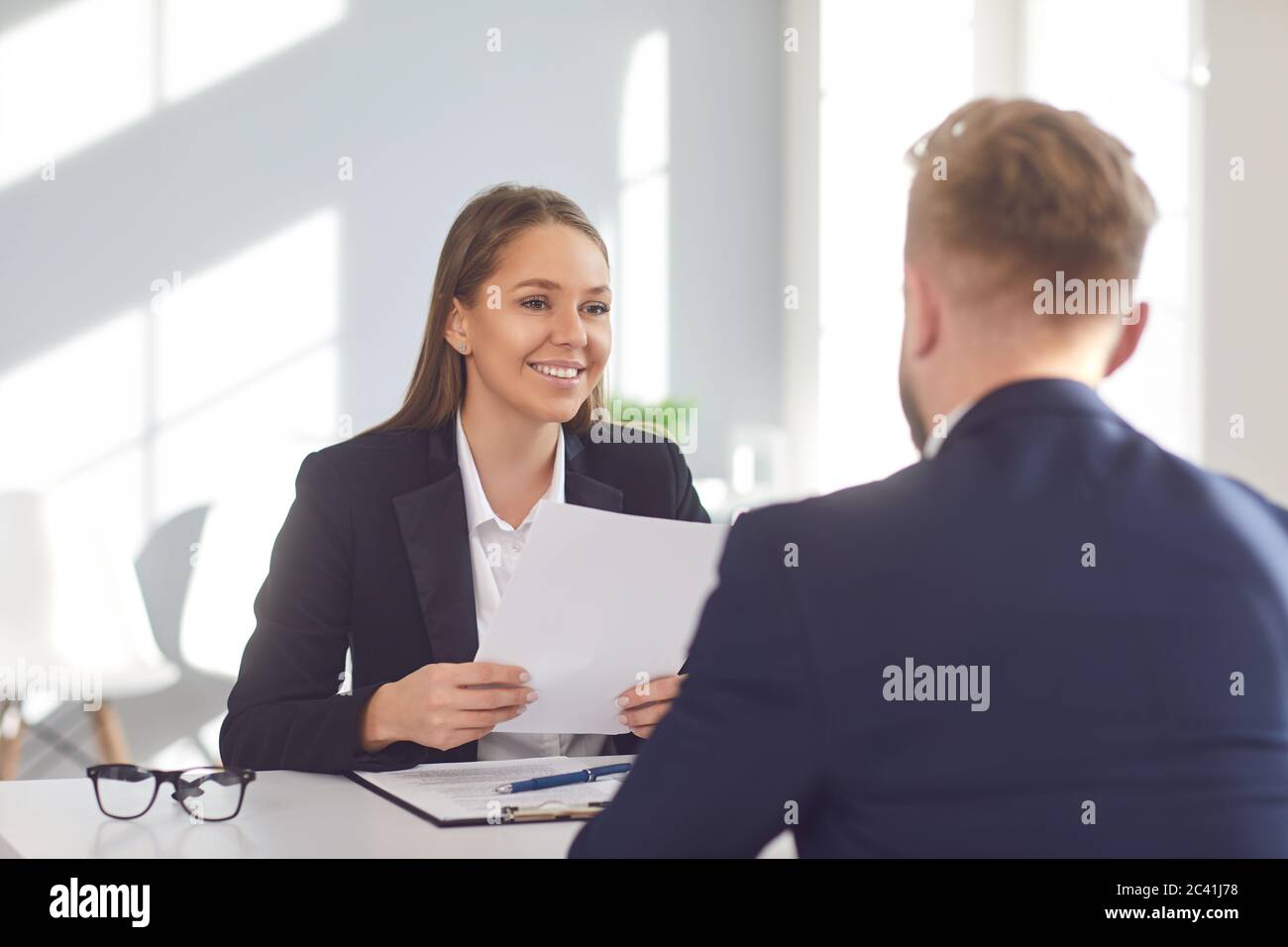 Erfolgreiches Interview. Positive Mädchen Arbeitgeber hört auf einen Arbeitssuchenden sitzen an einem Tisch im Büro. Stockfoto