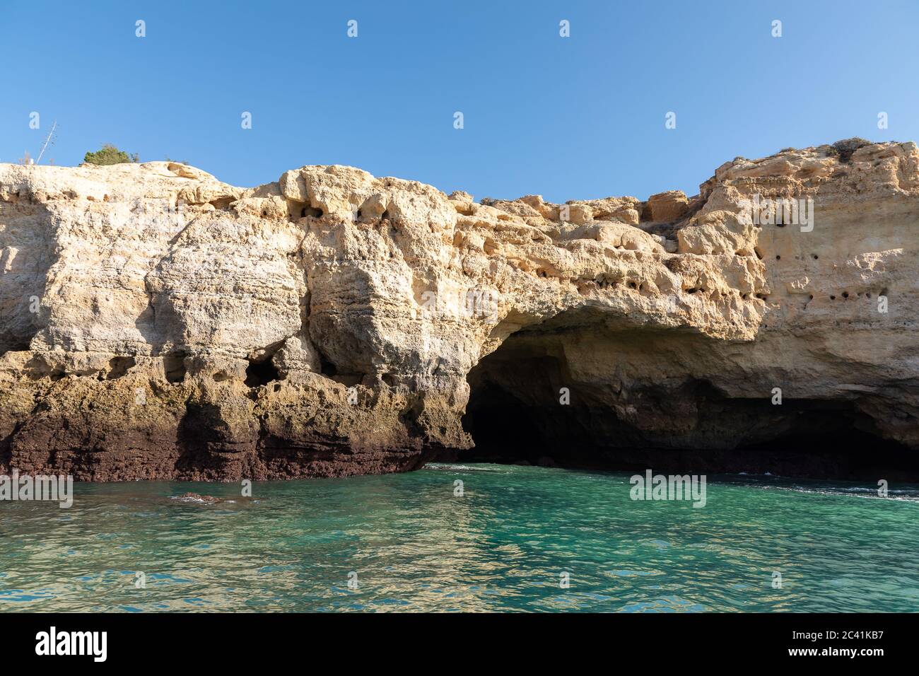 Landschaft mit den berühmten Benagil Höhlen, klarem blauen Himmel, Sandsteinklippen und Ausflugsboot an der Algarve Küste in Portugal Stockfoto