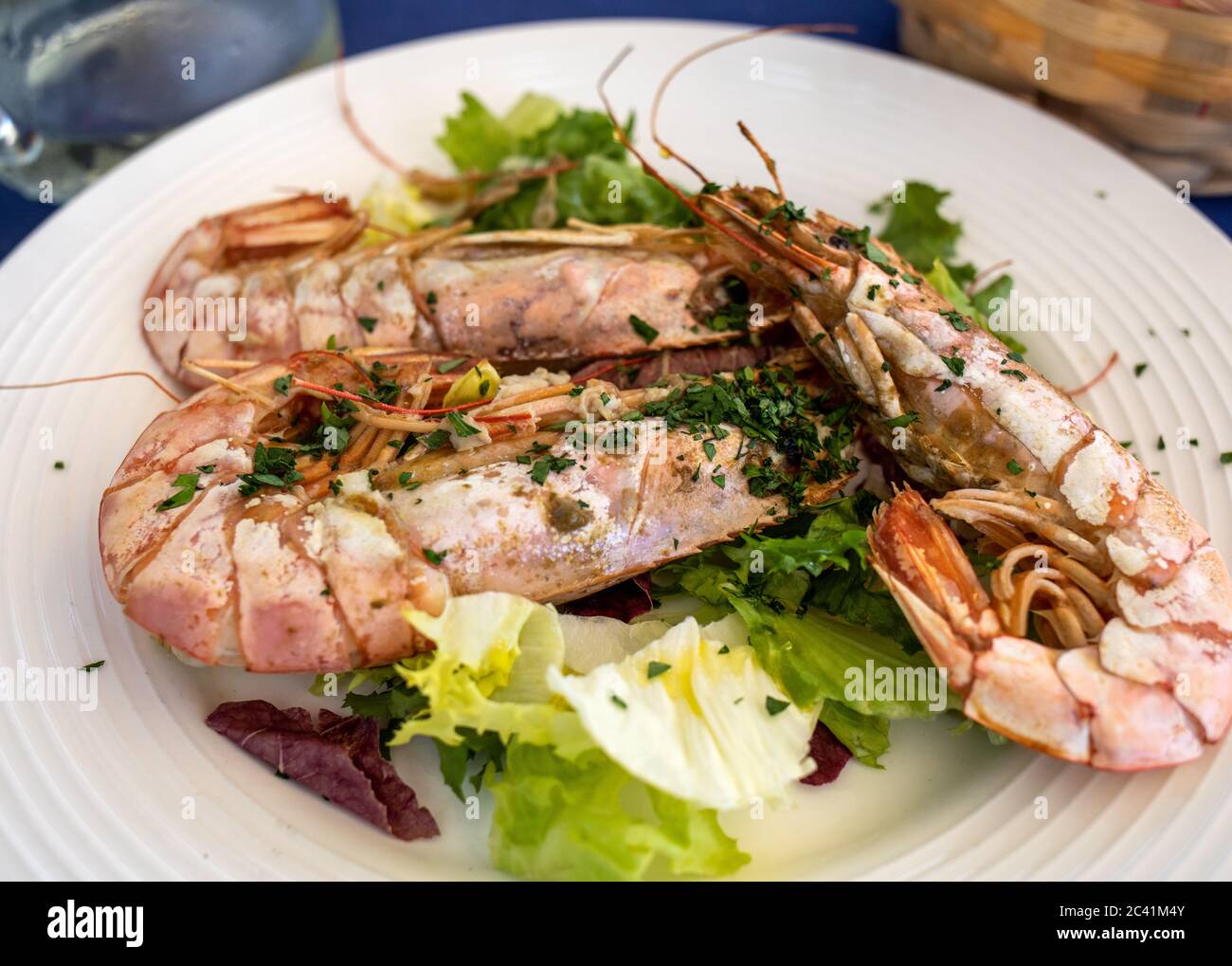 Große gebratene Garnelen mit Salat auf weiße Platte Stockfoto