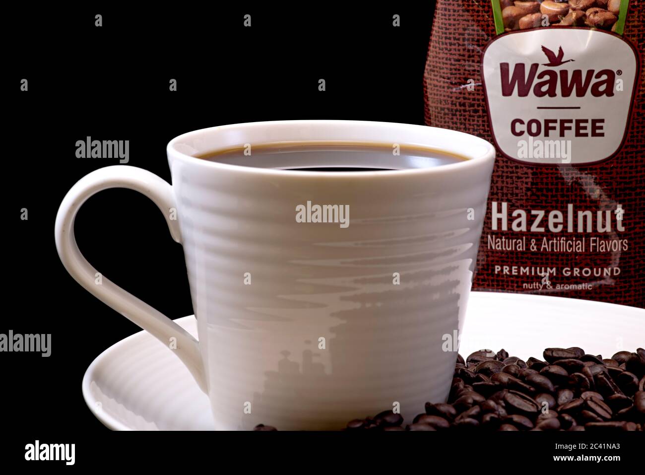 Wawa Haselnuss-Kaffeetasche Nahaufnahme mit einer gebrauten Tasse Wawa-Kaffee, weißer Tasse auf einem weißen Teller, Kaffeebohnen und einem schwarzen Hintergrund für Ausschnitte Stockfoto