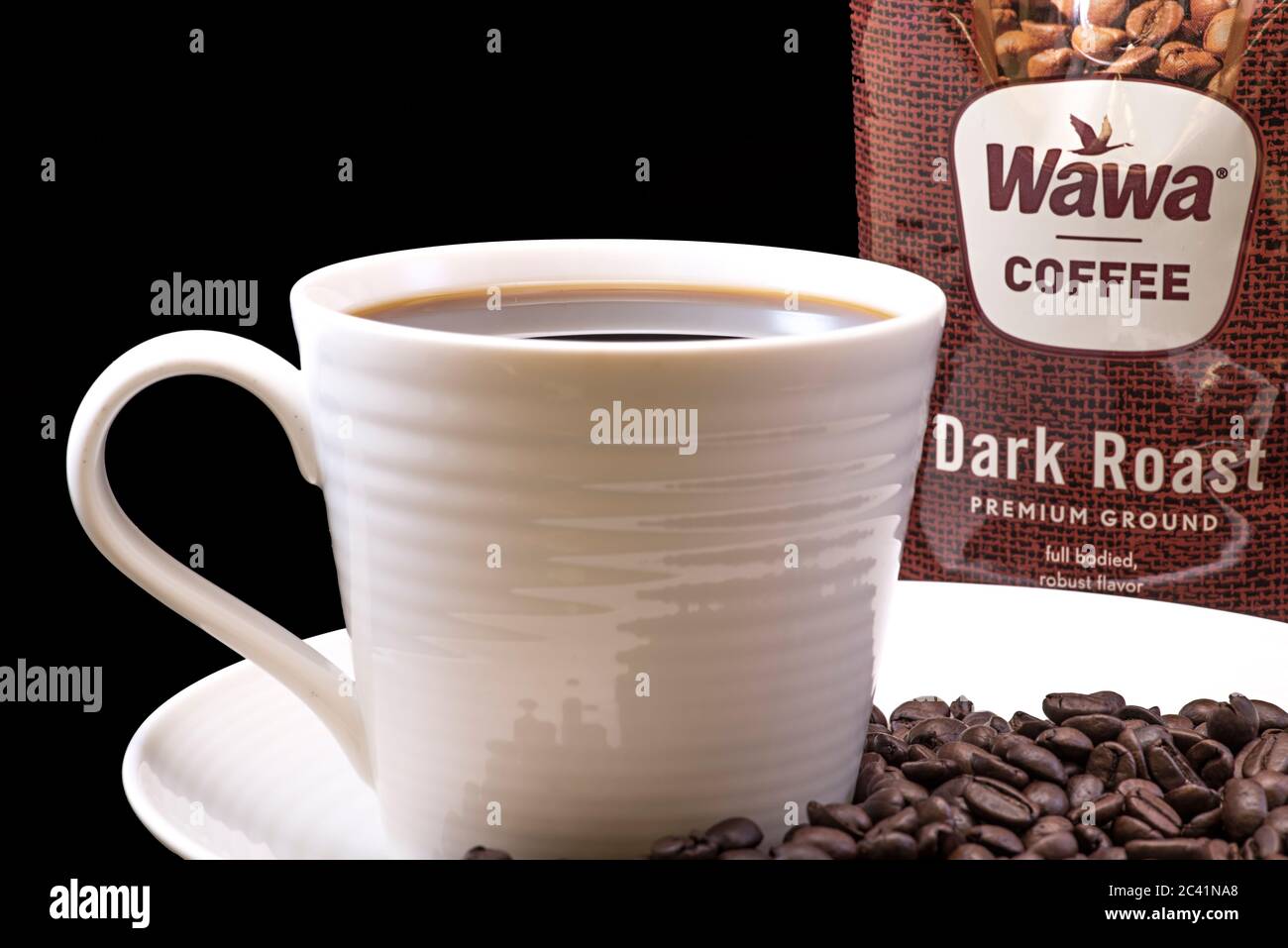 Wawa dunkel gebratene Kaffeetasche Nahaufnahme mit einer gebrauten Tasse Wawa Kaffee weißen Tasse auf einem weißen Teller, Kaffeebohnen und einem festen schwarzen Hintergrund für Ausschnitte Stockfoto