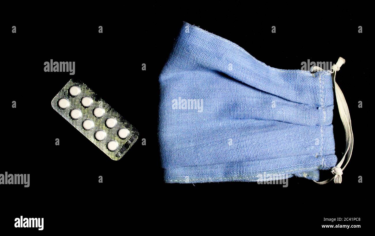 Dies ist ein Bild von hausgemachten wiederverwendbaren Gesichtsmaske verwendet, um uns vor der Corona-Pandemie und einem Streifen von medizinischen Tabletten zu schützen. Stockfoto