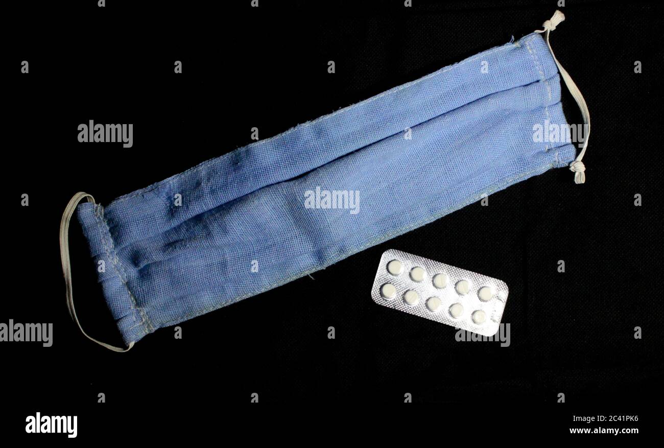 Dies ist ein Bild von hausgemachten wiederverwendbaren Gesichtsmaske verwendet, um uns vor der Corona-Pandemie und einem Streifen von medizinischen Tabletten zu schützen. Stockfoto