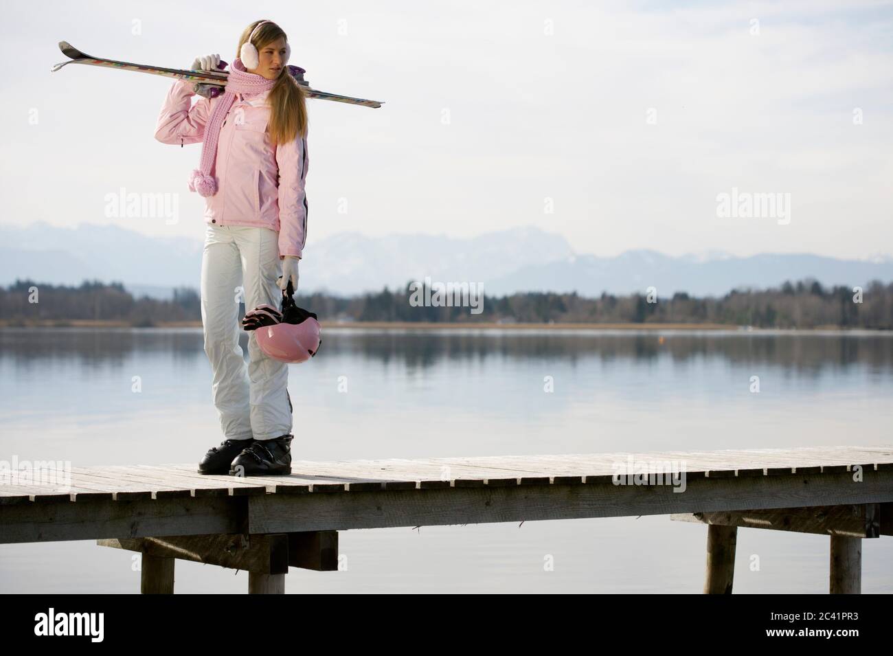 Junge Frau in Skibekleidung auf einem hölzernen Steg - See - Kontrast Stockfoto