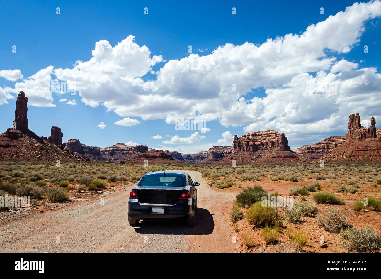 Auto auf einer unbefestigten Straße in einer malerischen Wüstenlandschaft mit Felsen im Hintergrund Stockfoto
