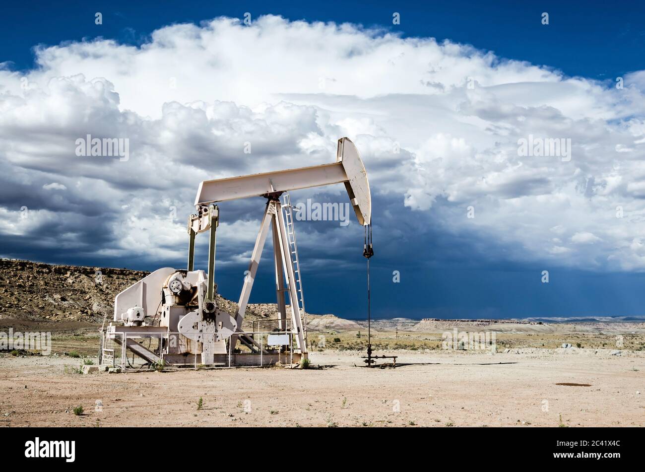 Ölpumpe in der Wüste mit dunklen Wolken eines Gewitters im Hintergrund Stockfoto