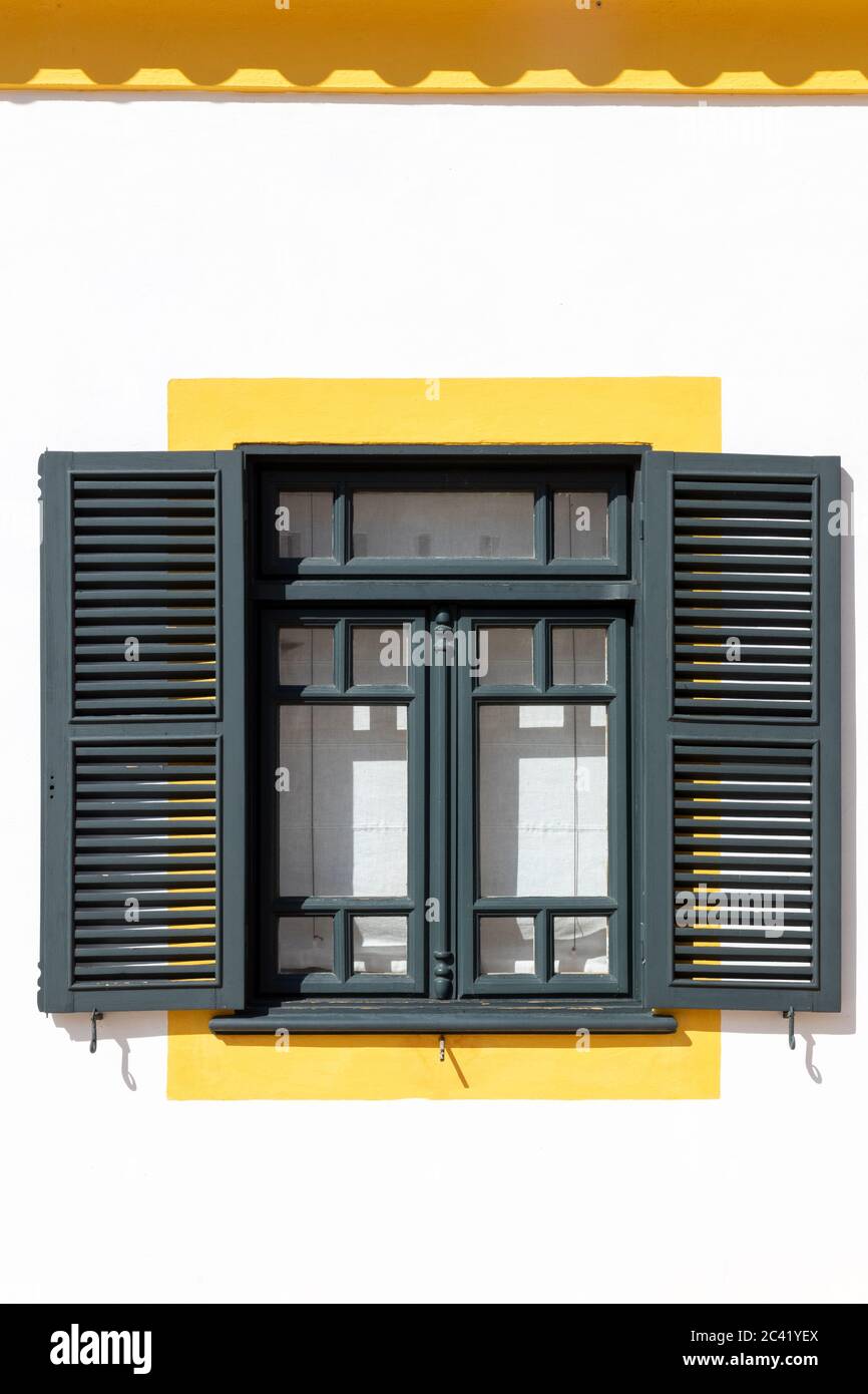 Außenansicht des weißen Hauses mit grünen Fenstern und Fensterläden mit gelben Zierleisten Stockfoto