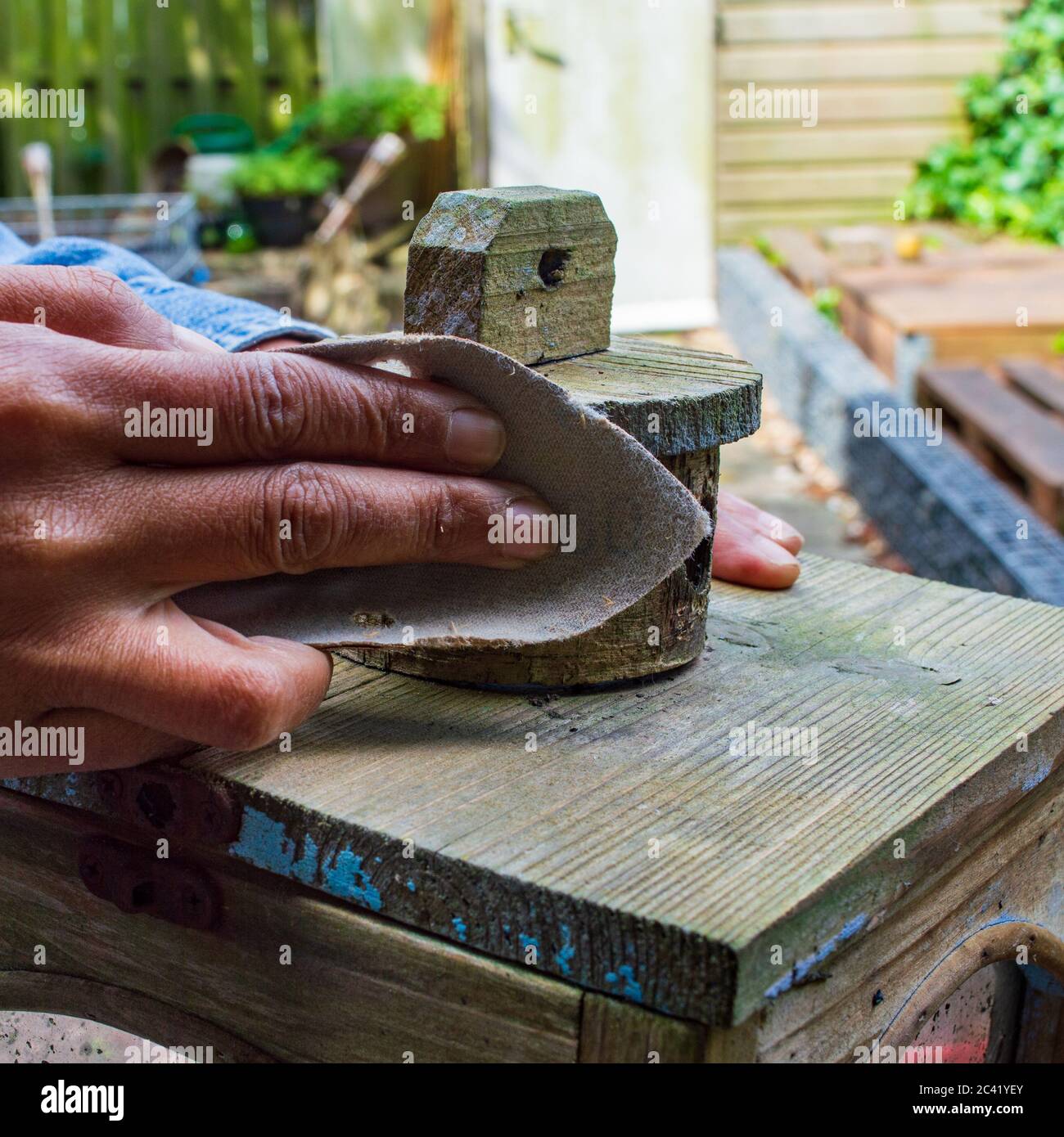 Nahaufnahme der Hand einer Frau der Farbe Schleifen einer hölzernen Ornament draußen im Hinterhof Stockfoto