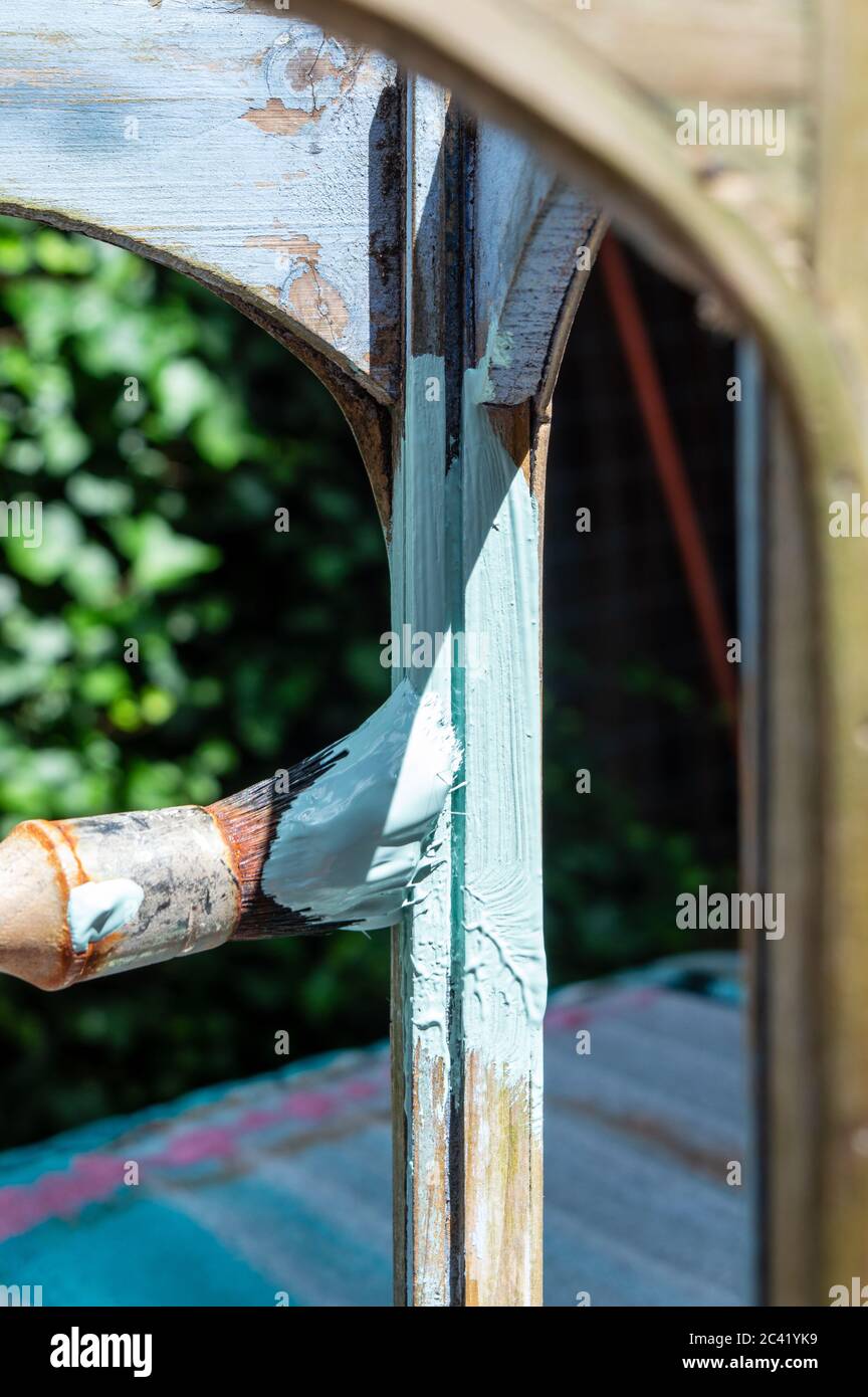 Jemand malt den Bogen und die Säule einer Laterne mit pastellgrüner Farbe Stockfoto