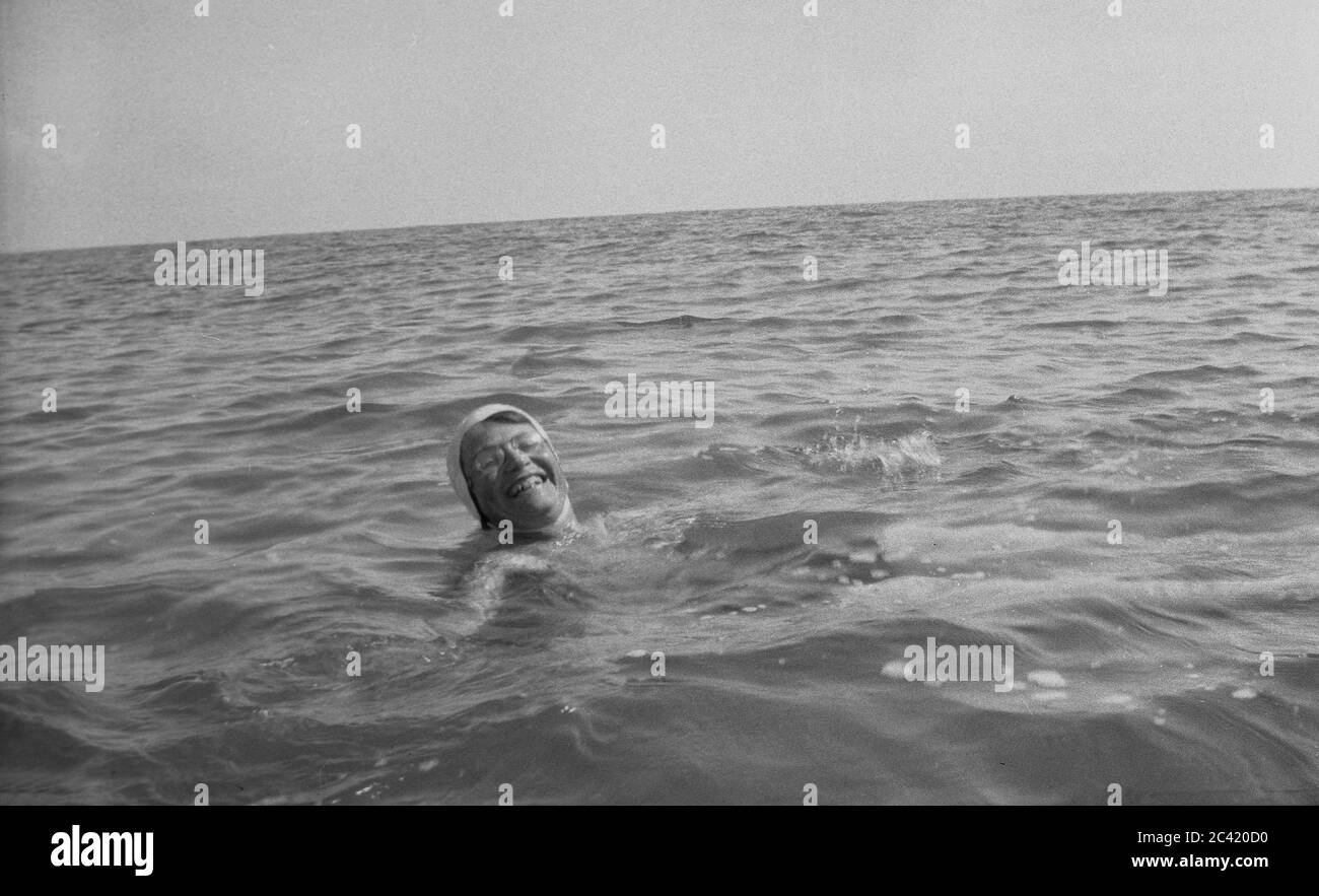 Im Urlaub, eine glückliche Dame mit Brille und Badehut, genießen das Wasser, während sie rückwärts ins Meer schwebt, Ende 40er Jahre, Anfang 1950er Jahre. Stockfoto