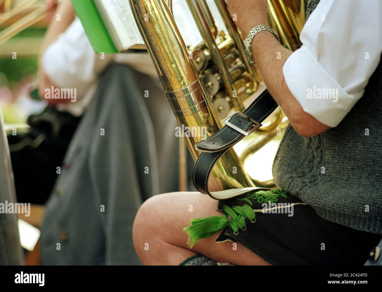 Zwei sitzende Männer in alpinem Kostüm spielen auf Blasinstrumenten Stockfoto