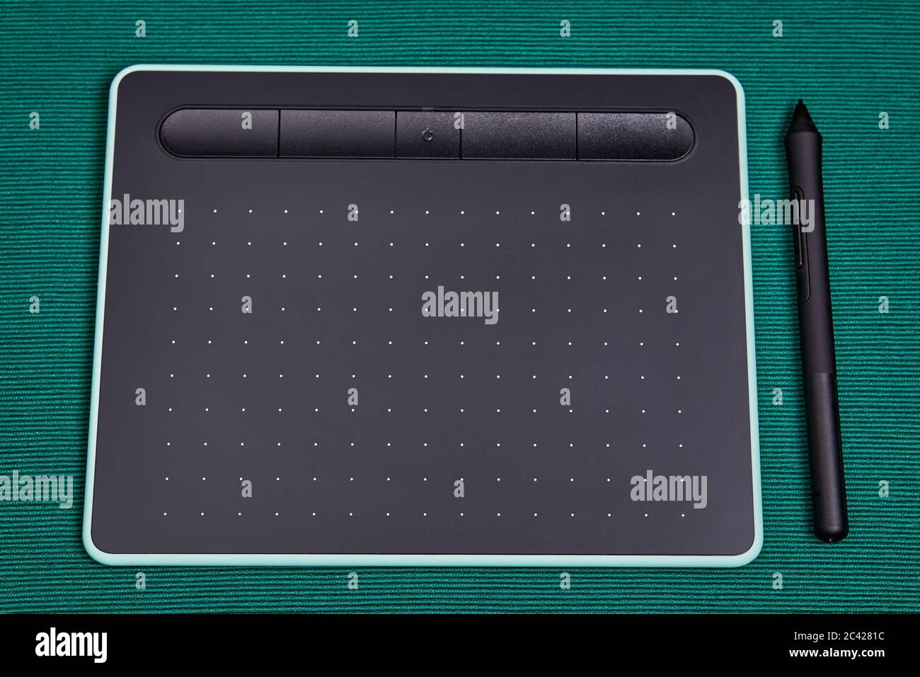 Auf einem mit einem grünen Tuch bedeckten Tisch liegt ein elektronisches Eingabegerät für einen PC, ein Grafiktablett mit einem Stylus-Stift. Zeichenbrett für Stockfoto