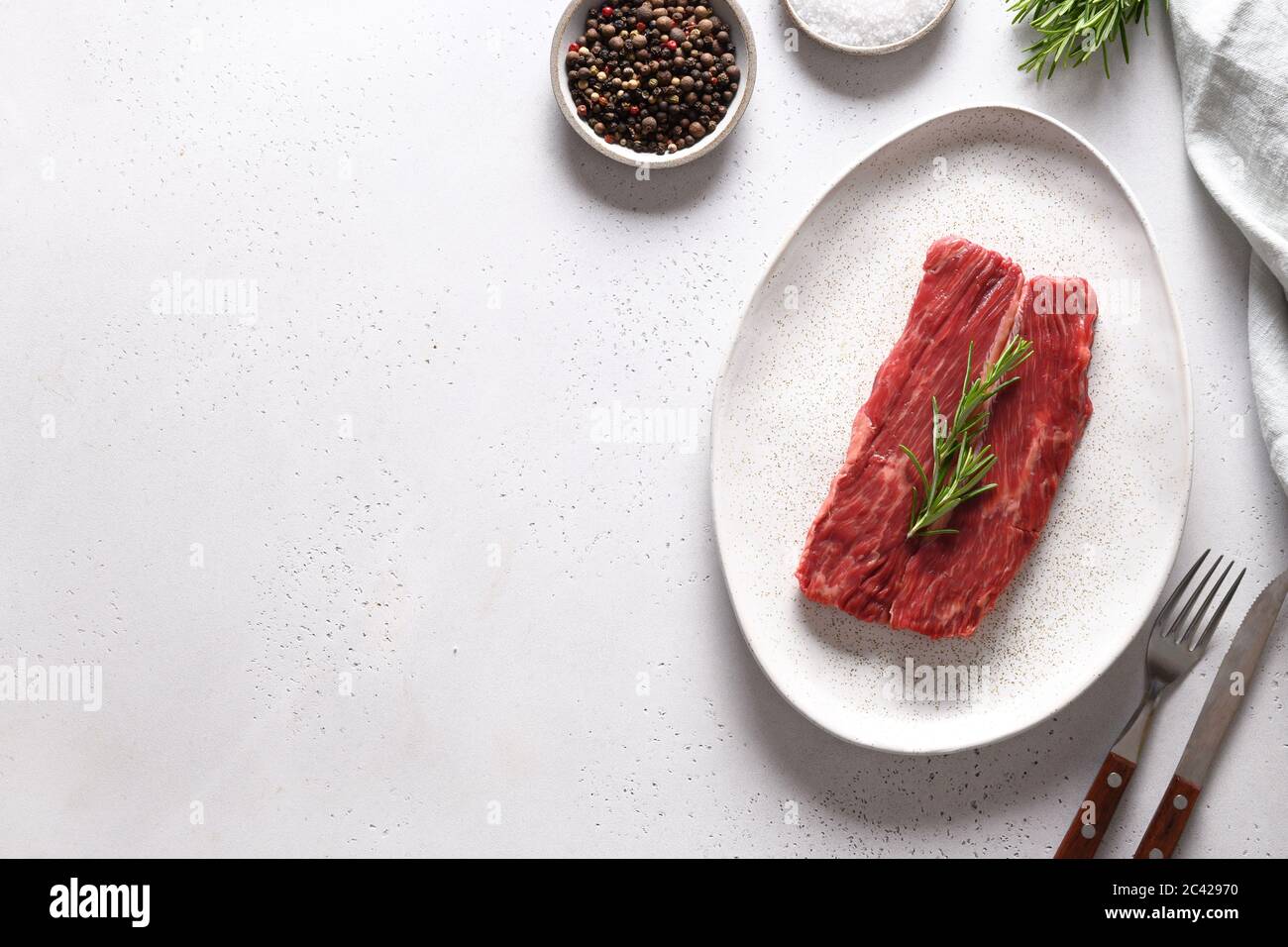Rohes Ribeye Steak mit Rosmarin auf Weiß. Speicherplatz kopieren. Stockfoto