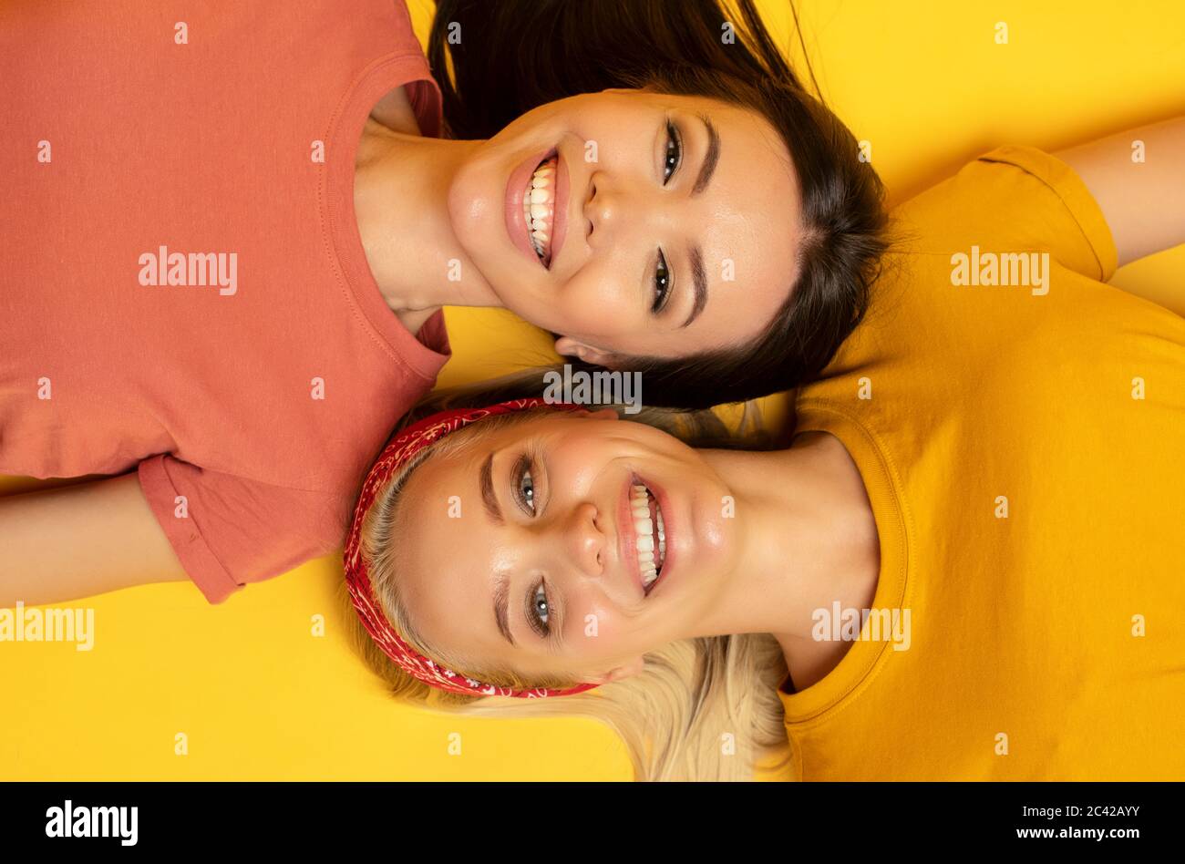 Zwei Freunde lächeln zusammen. Gelber Hintergrund. Freundschaftskonzept Stockfoto