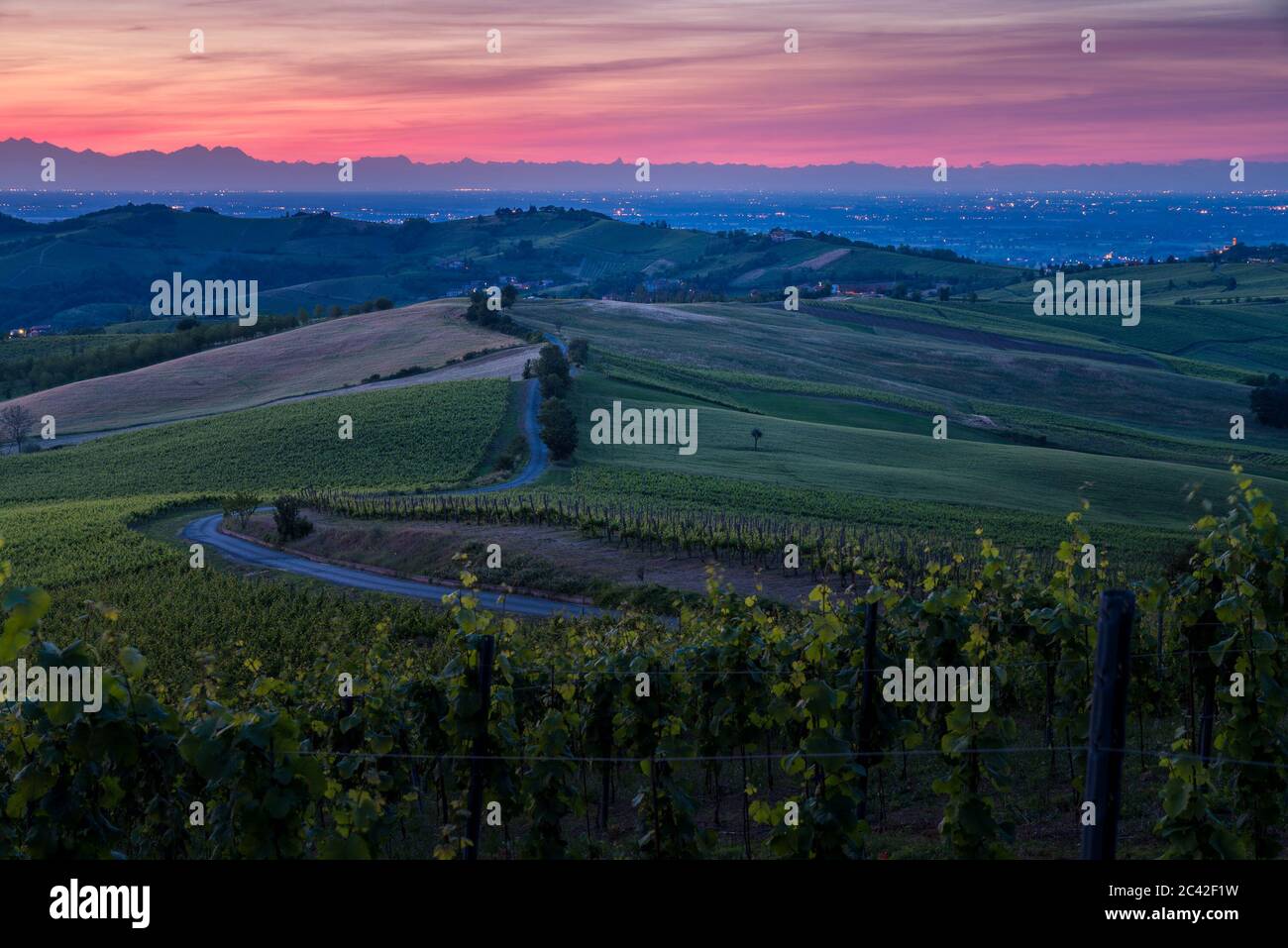 Erstaunliche rot-lila Sonnenuntergang über Oltrepo' Pavese Hügel mit Weinbergen und Landstraßen Stockfoto