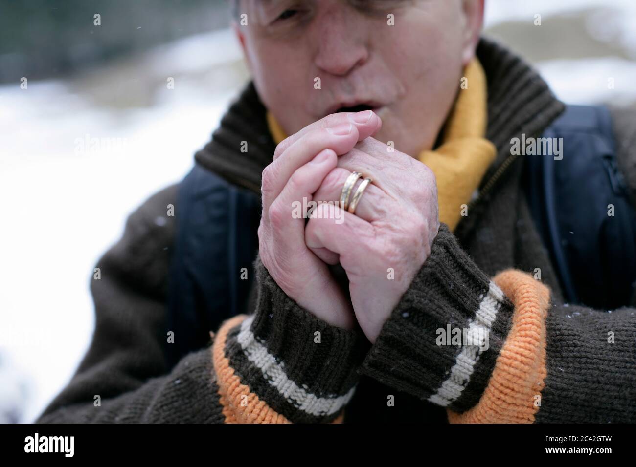 Ein alter Mann wärmt seine Hände Stockfoto