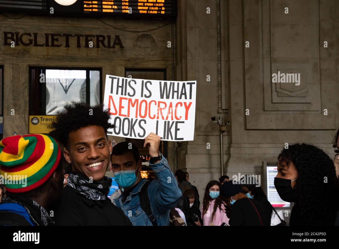 Protestler mit Plakat "so sieht Demokratie aus", gerade außerhalb des Mailänder Hauptbahnhofs, während der Protestversammlung in Solidarität mit der BLM-Bewegung Stockfoto