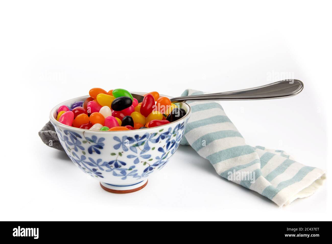 Eine kleine Suppenschüssel mit bunten Jelly Beans und einem Löffel, als ob als Mahlzeit auf Weiß isoliert gegessen Stockfoto