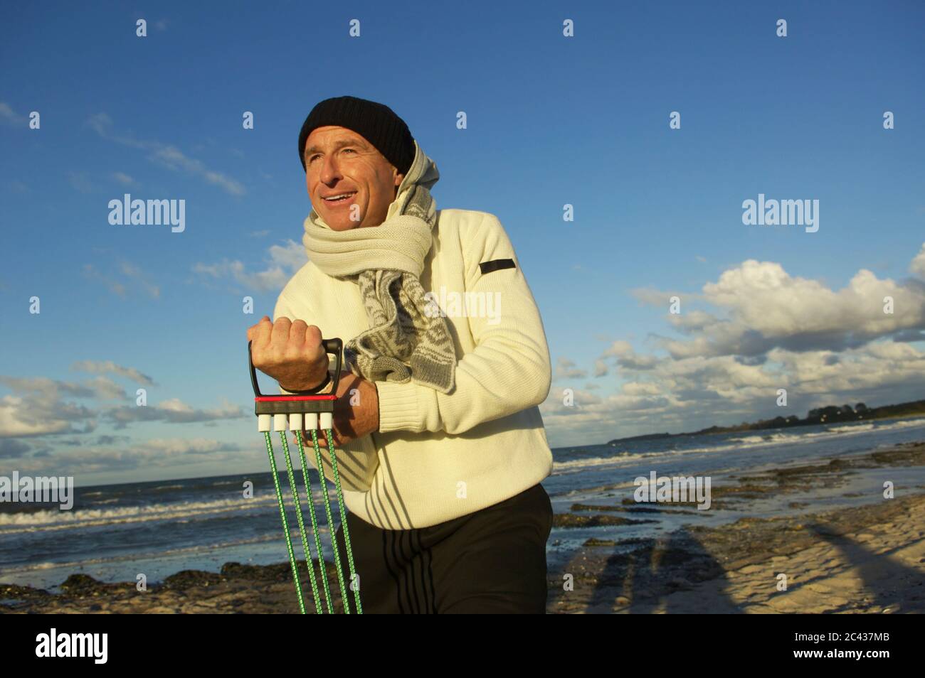 Älterer Mann trainiert mit einem Expander am Ostseestrand, Timmendorfer Strand, Schleswig-Holstein, Deutschland Stockfoto