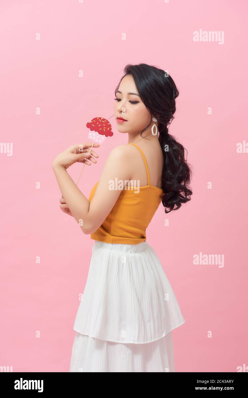 Rosa Hintergrund glücklich Frau hält Kuchen aus Papier auf einem Stock machen Stockfoto