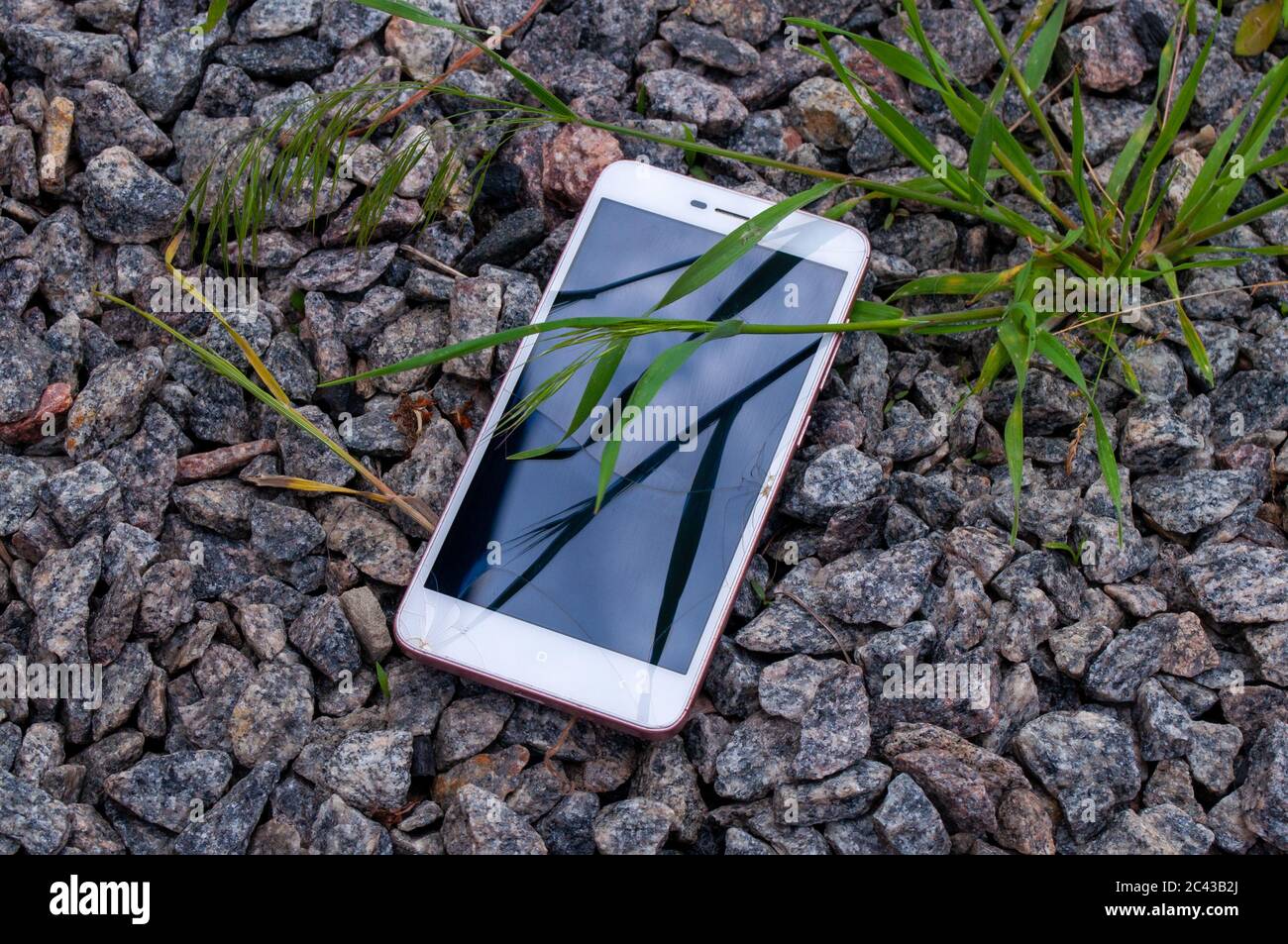 Smartphone mit einem defekten Bildschirm. Gebrochenes Telefon auf den Steinen. Stock Foto Stockfoto