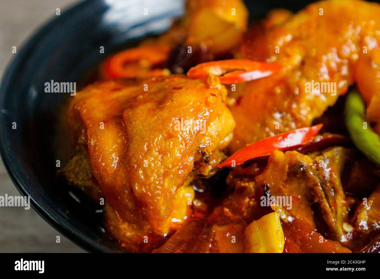 Gebratenes Huhn mit würziger Süß- und Sauersoße, thailändischem Chili, rotem Chili und Kartoffeln gekocht. Stockfoto