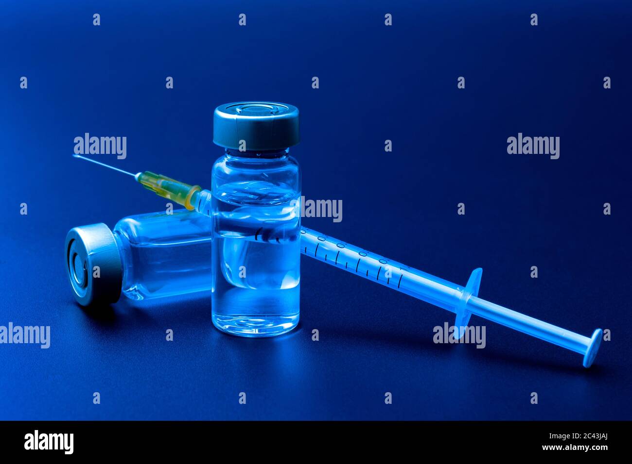 Impfstoffe, Botulinumtoxin und Insulinampullen – Konzeptthema mit Glasfläschchen mit klarer Flüssigkeit neben einer Spritze und einer auf b isolierten hypodermischen Nadel Stockfoto