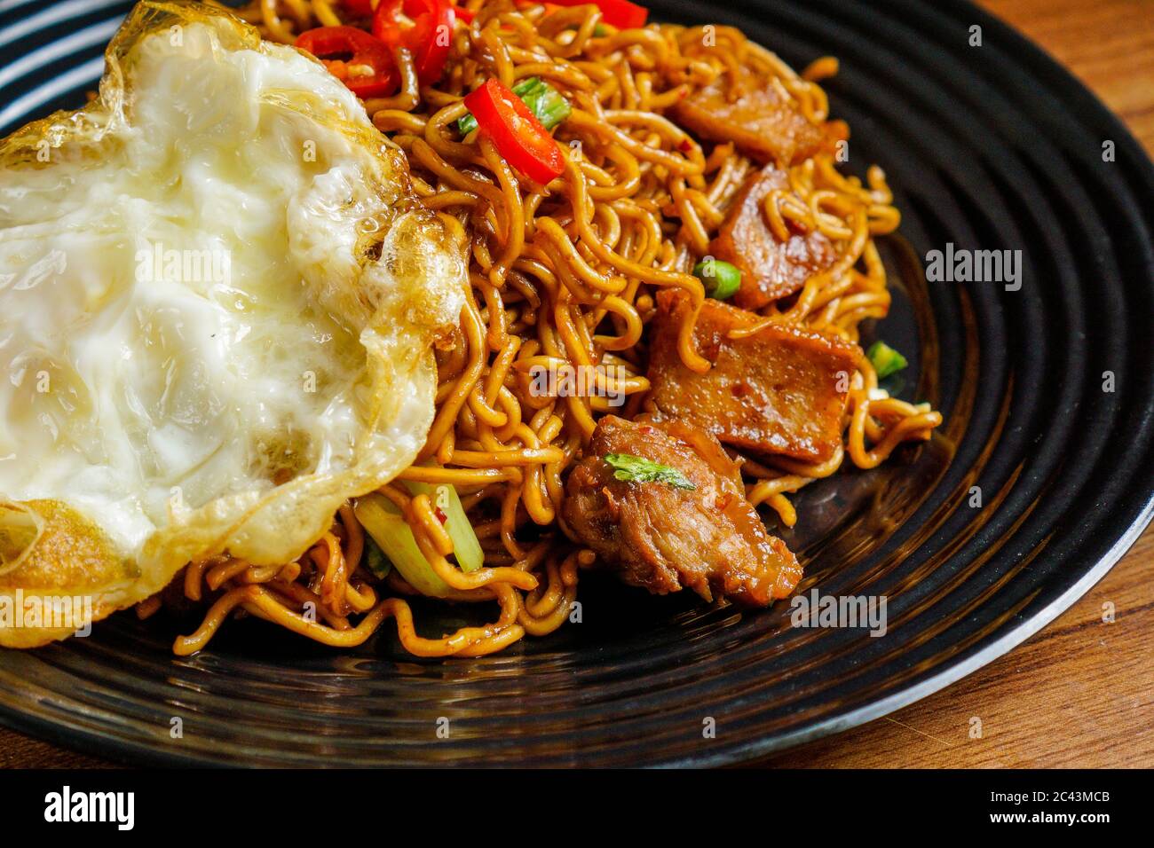 Dry Instant Noodle, malaysische maggi Goreng mamak oder würzige Dry Curry Instant Nudeln mit sonnigen Seite up Ei und Rindfleisch. Stockfoto