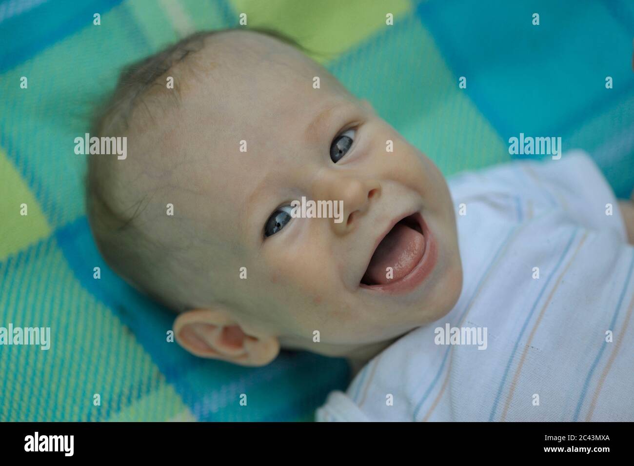 Fröhliches Baby liegt auf einer Decke Stockfoto
