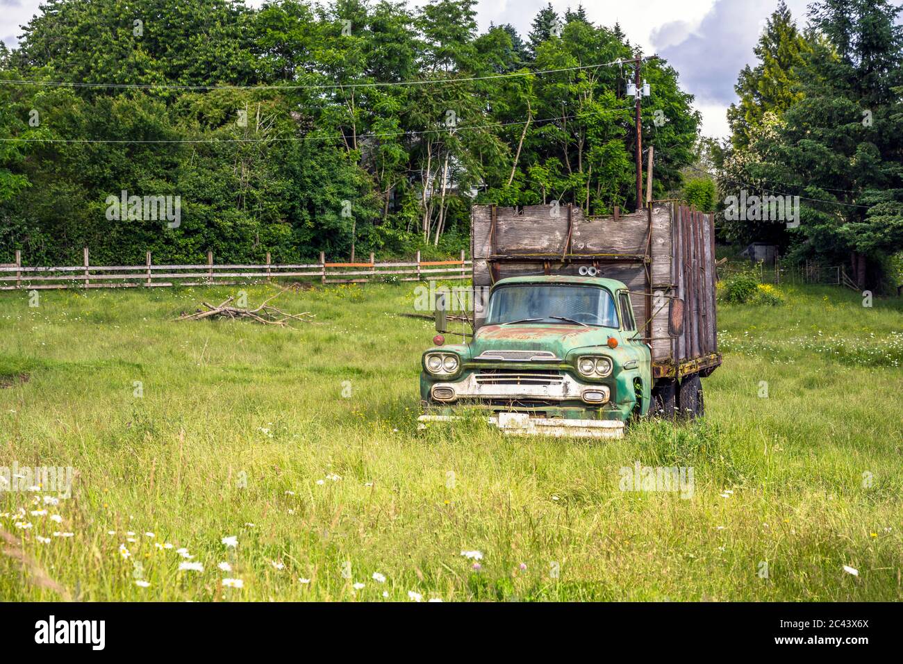 Kleine alte rostigen Retro-Oldtimer-grünen LKW mit handgefertigten Sperrholz Anhänger stehen auf der breiten offenen Wiese mit hohem grünen Gras als Symbol für eine harte Stockfoto