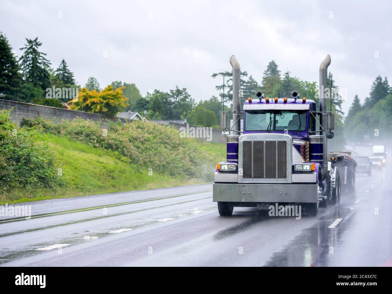 Leistungsstarke klassische industrielle Qualität große Rig blau semi-Truck mit hohen Auspuffrohren und Flachbett Sattelauflieger läuft auf der Gefahr nass regnet Straße wit Stockfoto