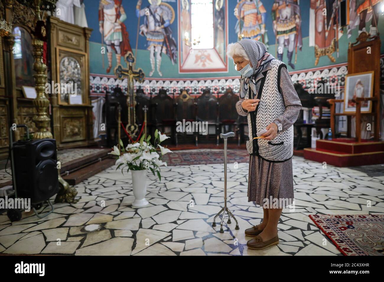 Snagov, Rumänien - 21. Juni 2020: Ältere Frau mit Covid-19 Maske betet vor einer orthodoxen christlichen Kirche. Stockfoto