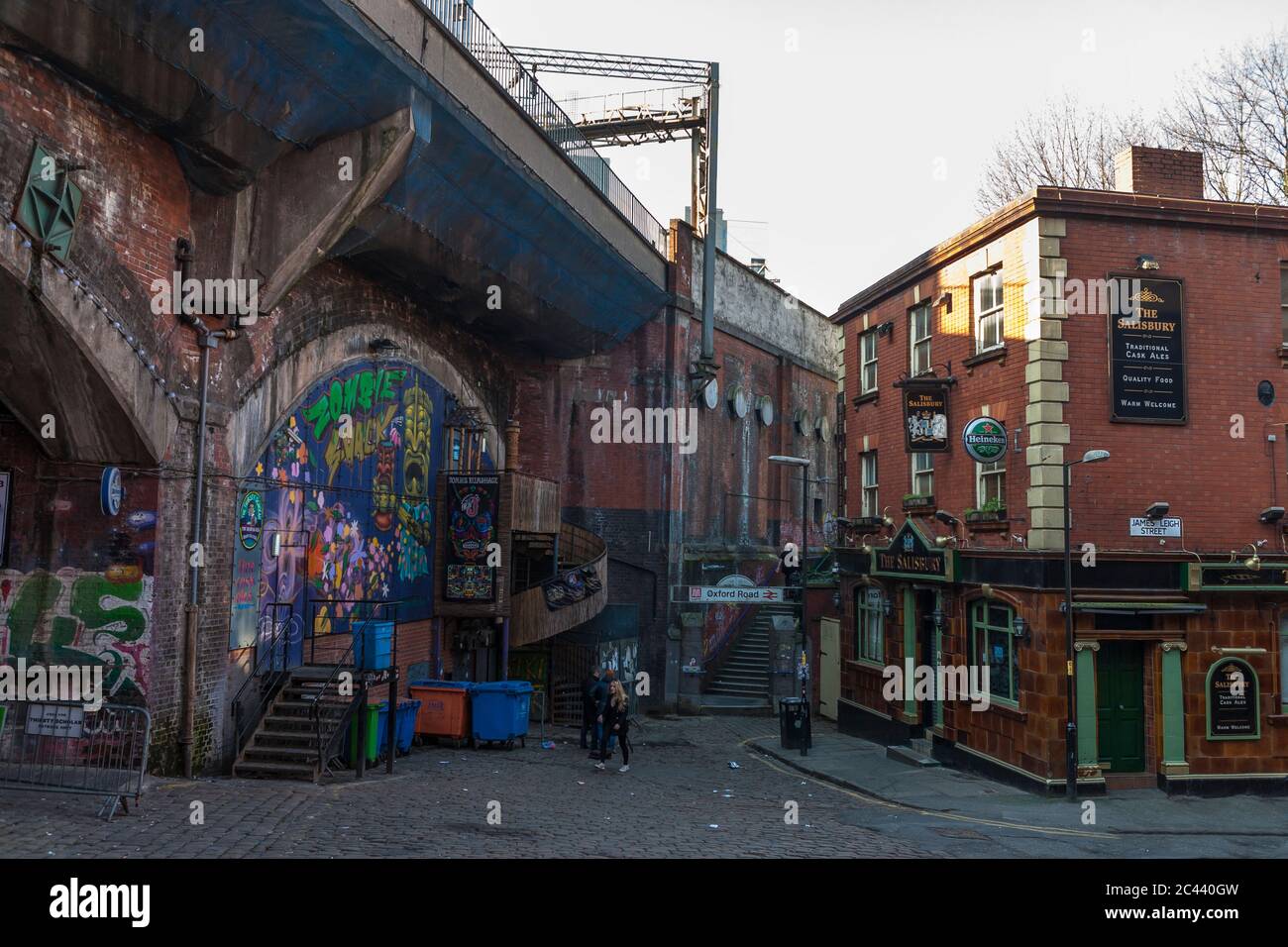 Grimmiges, mit Graffiti bedecktes Eisenbahnviadukt dominiert ein Pub, Wakefield St, Manchester, England, Großbritannien Stockfoto