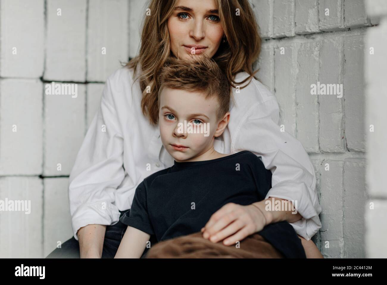 Portrait von selbstbewussten Mutter mit Sohn sitzt auf Nische zu Hause Stockfoto