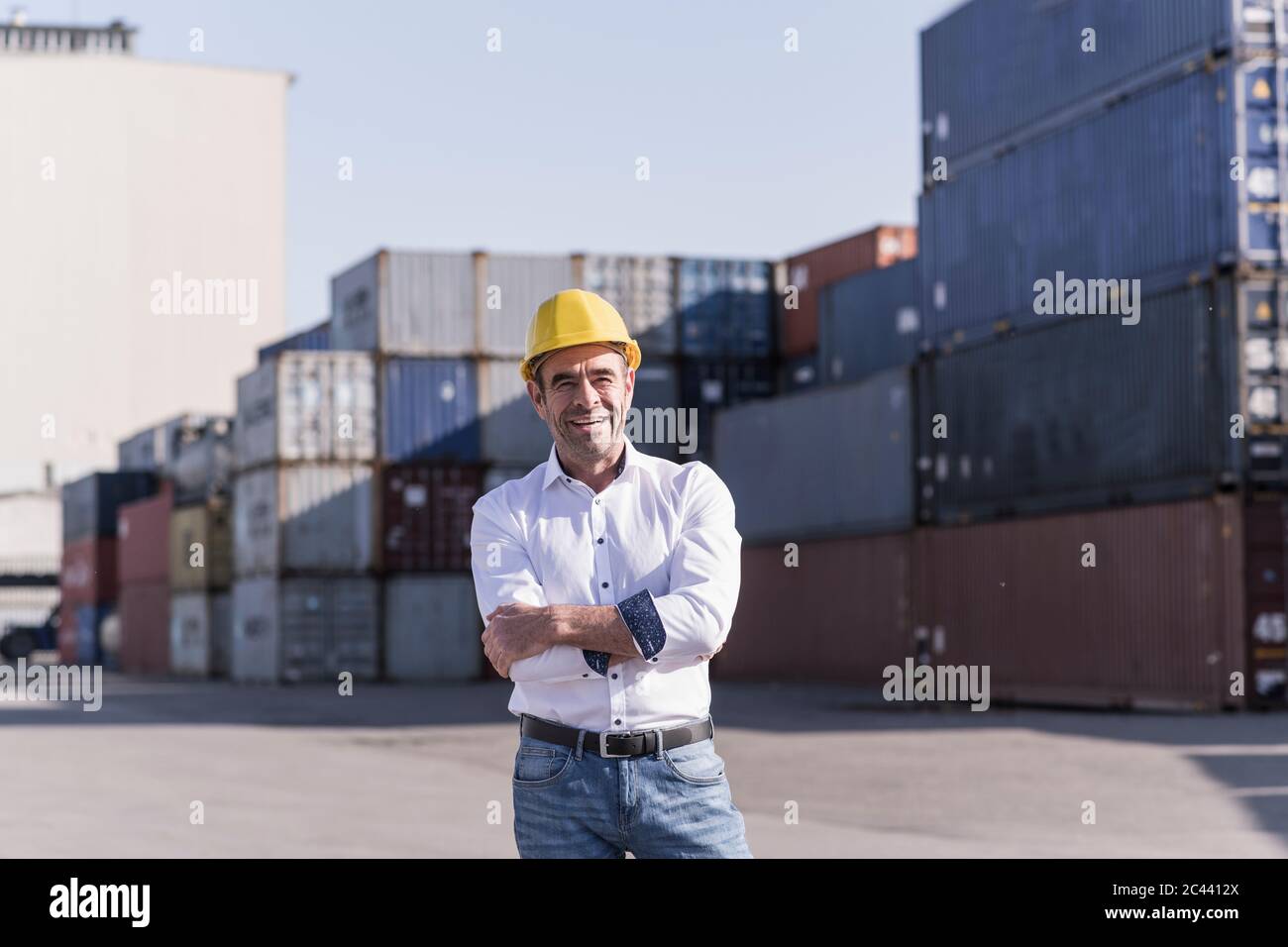 Portrait des selbstbewussten Geschäftsmann trägt Schutzhelm vor der Ladung Container Stockfoto
