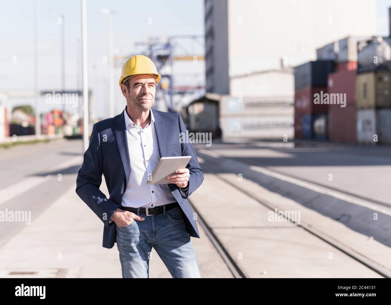 Portrait of content Geschäftsmann trägt Schutzhelm mit digitalen Tablet auf Industriegelände Stockfoto