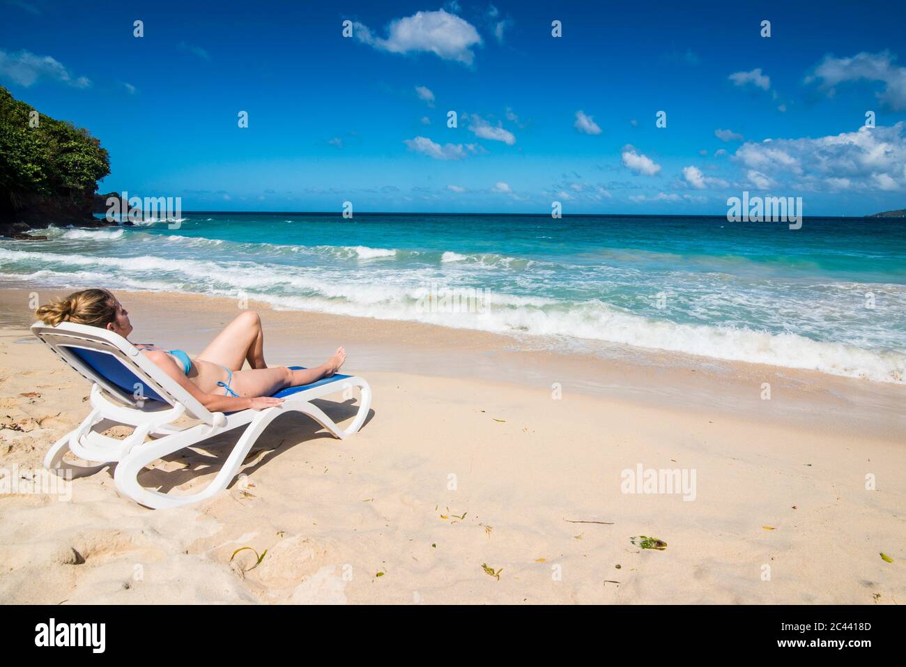 Frau relaxen im Liegestuhl am Strand gegen den blauen Himmel, Grande Anse, Grenada, Karibik Stockfoto